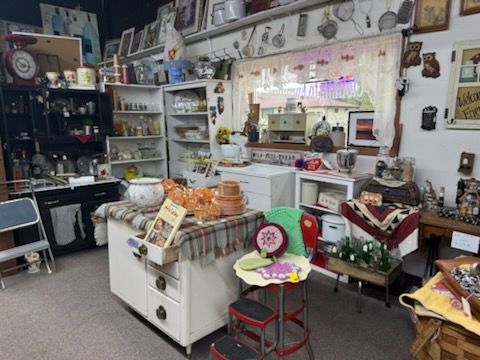 Cluttered vintage shop interior with shelves, pottery, and assorted decor items