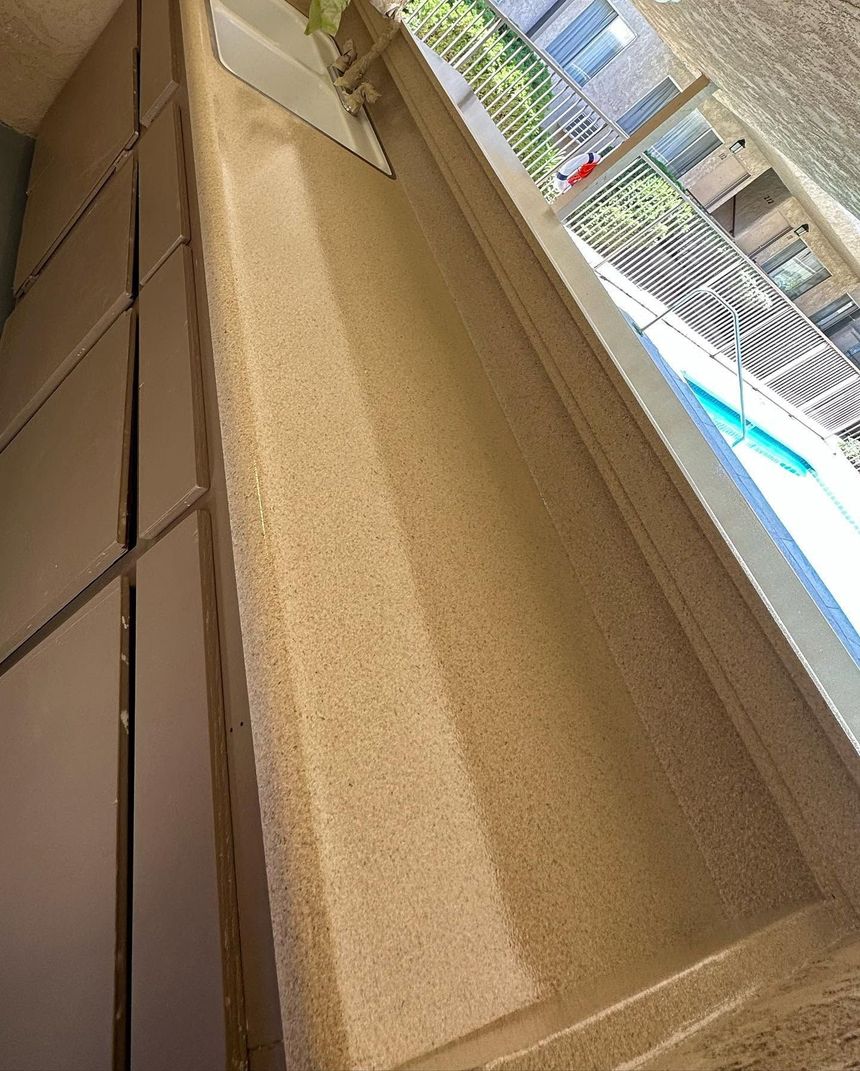 Long cardboard box beside a pool deck, with buildings and umbrellas in the background