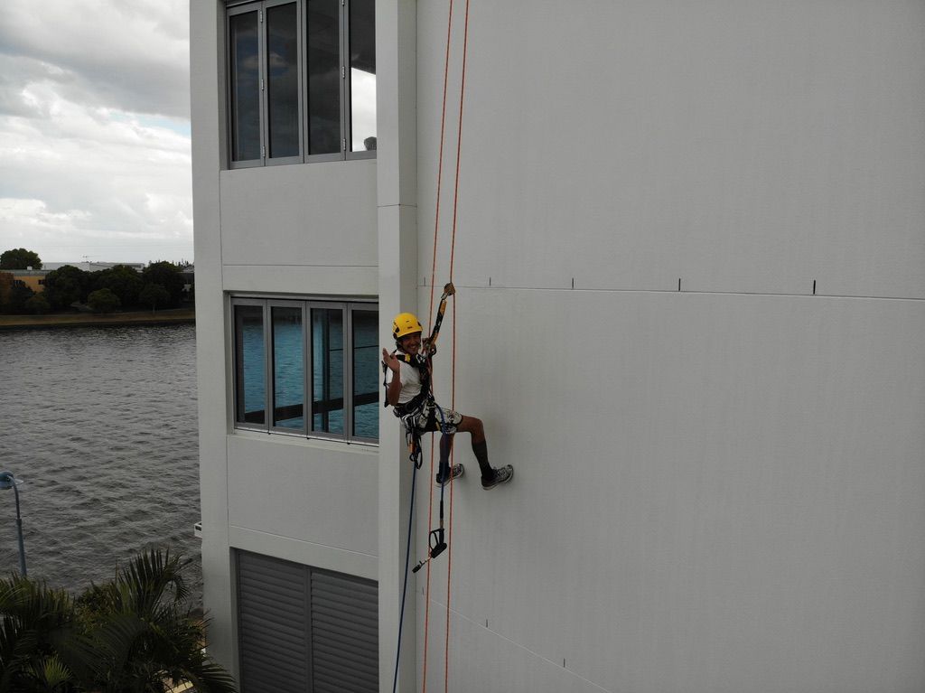 A Man is Climbing Up the Side of a Building — Dezigner Finishes Professional Painting & Decorating in Maroochydore, QLD
