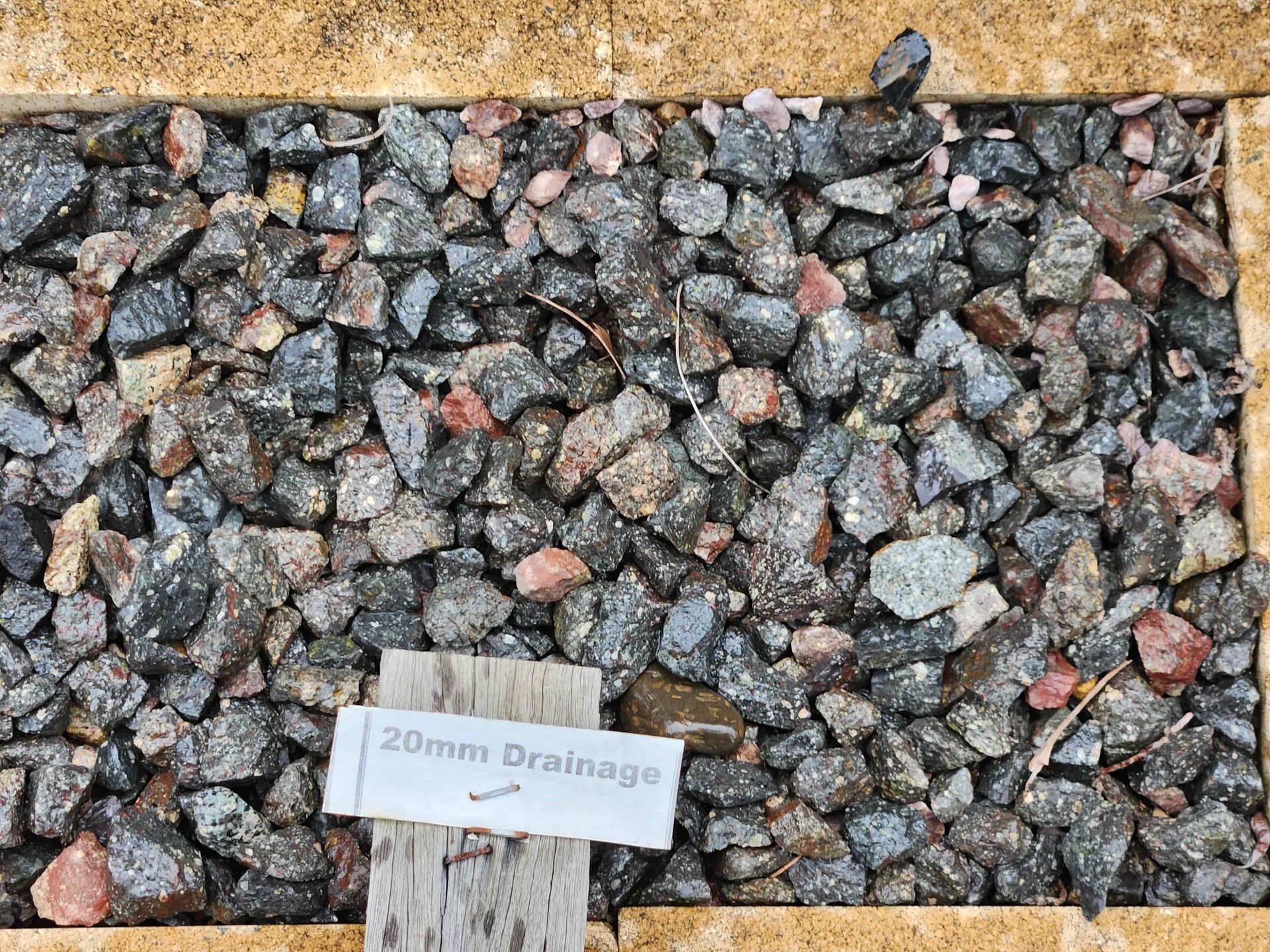 A Pile of Rocks With a Sign That Says 20mm Drainage '' on It — T&G Sand and Gravel In Sippy Downs, QLD