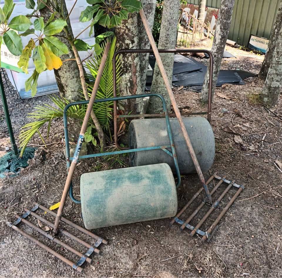A Lawn Roller is Sitting on the Ground Next to a Rake — T&G Sand and Gravel In Sippy Downs, QLD