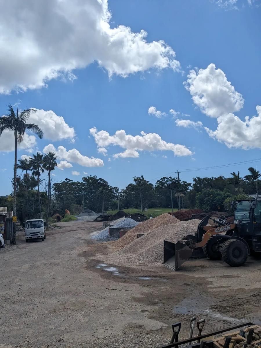 A Tractor Is Parked In A Gravel Lot With Palm Trees In The Background — T&G Sand and Gravel In Nambour, QLD