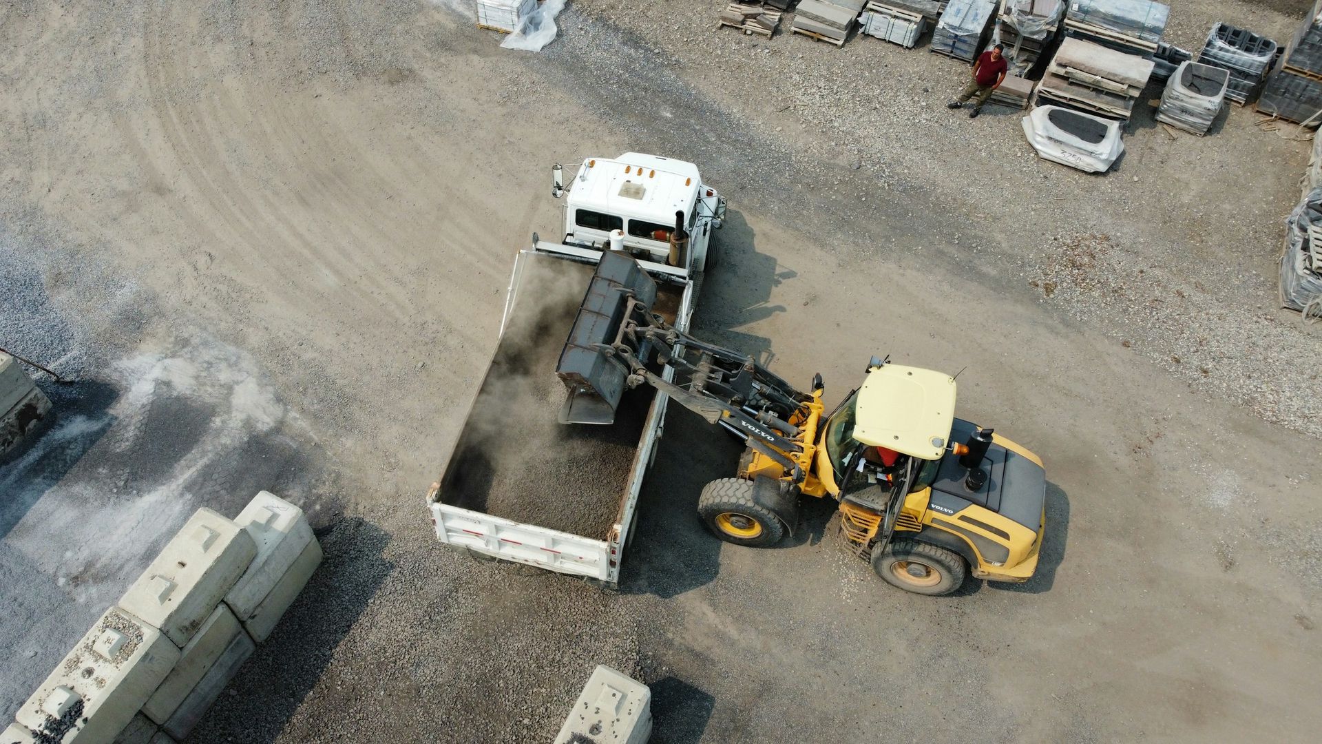 Aerial view of two construction vehicles loading dirt into a dump truck at a worksite