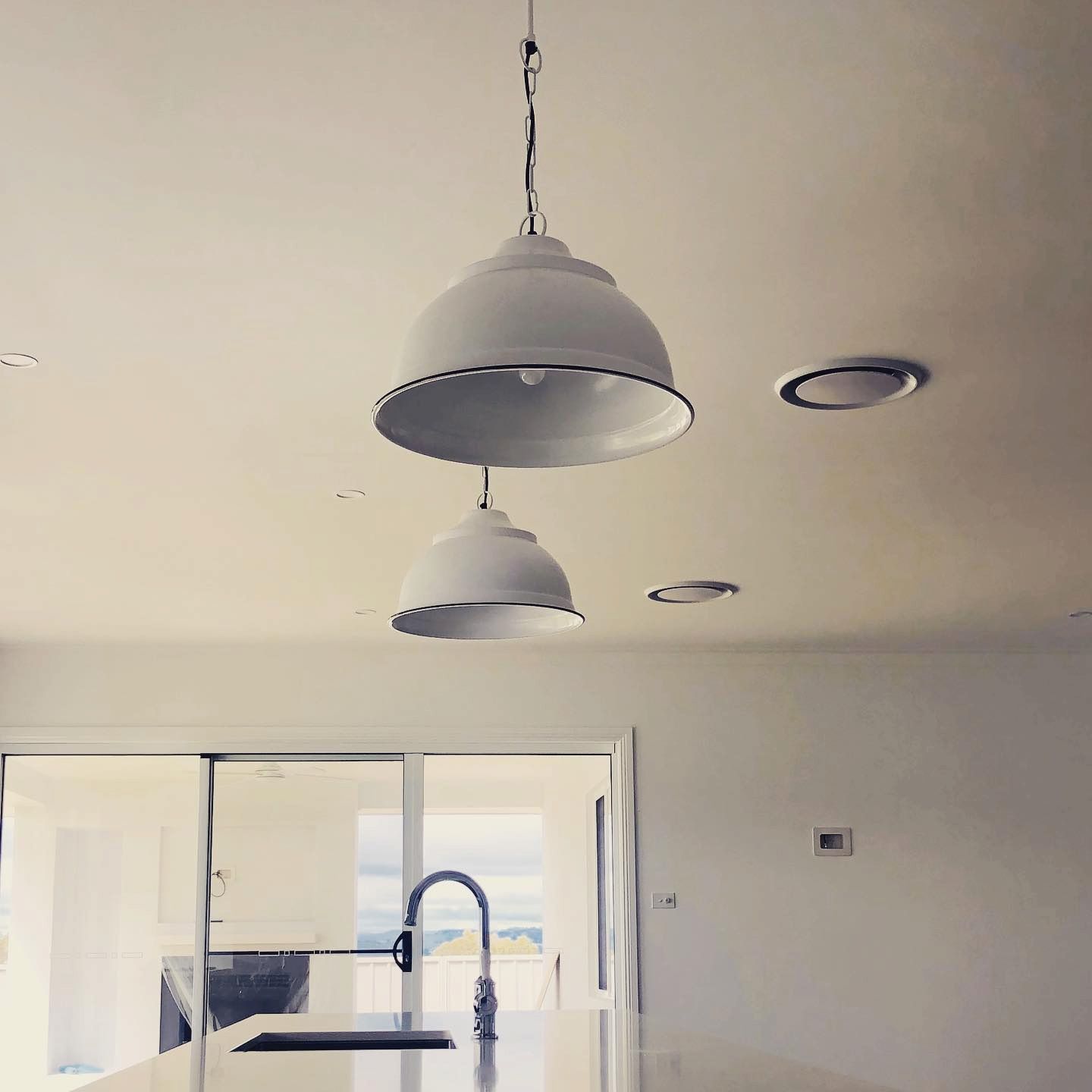 Two White Pendant Lights Hanging Over a Kitchen Island, With a Sink — Brett Cox Electrical and Solar in Gumly Gumly, NSW