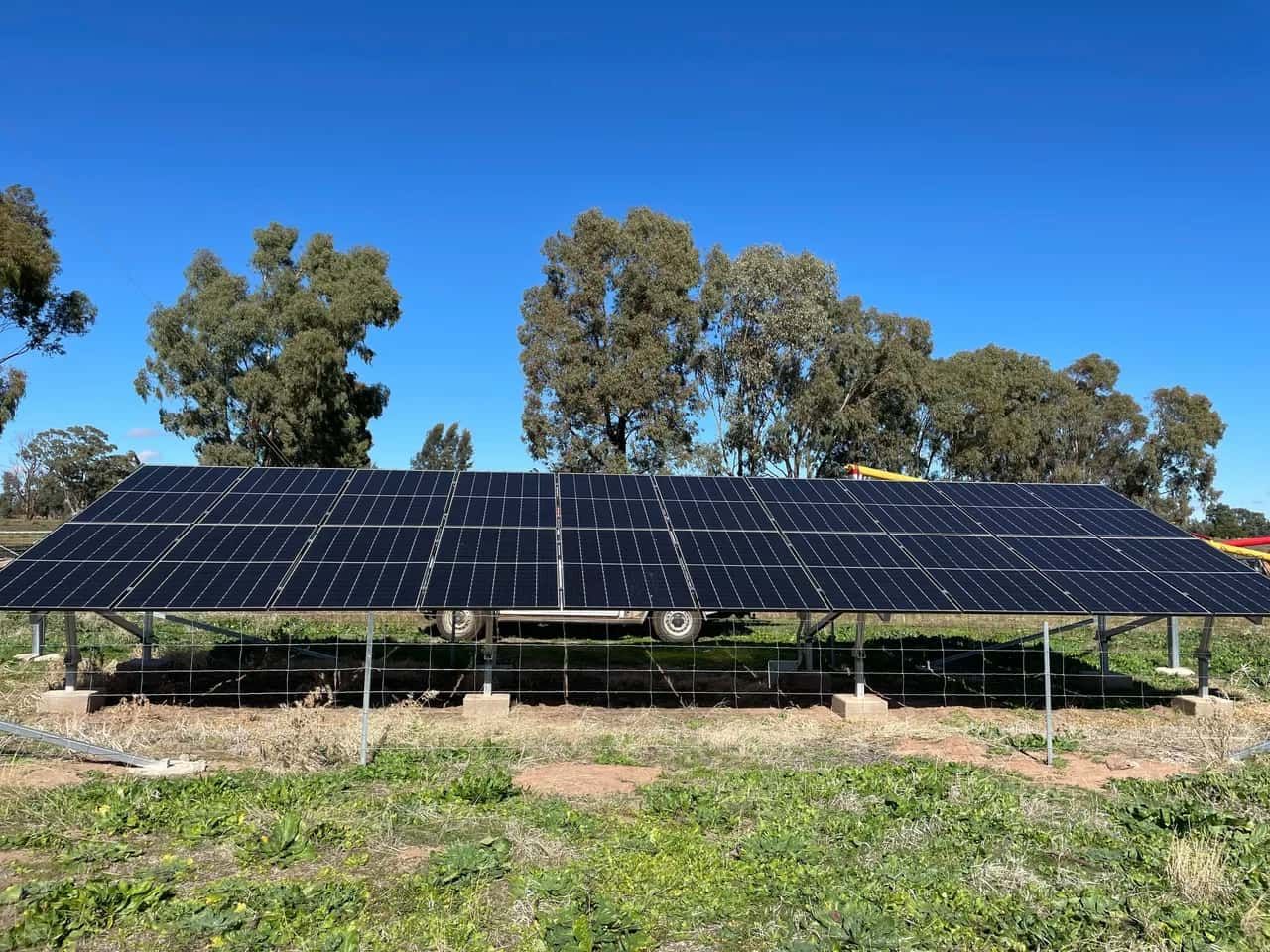Solar Panels Installed in a Field With Blue Sky and Trees — Brett Cox Electrical and Solar in Gumly Gumly, NSW