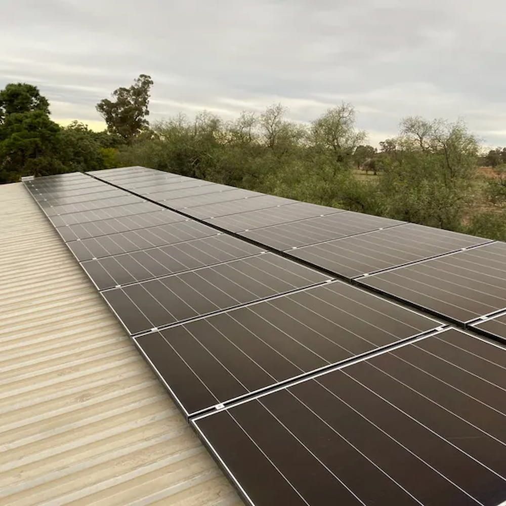 Solar Panels Installed on a Metal Roof Against a Cloudy Sky — Brett Cox Electrical and Solar in Gumly Gumly, NSW