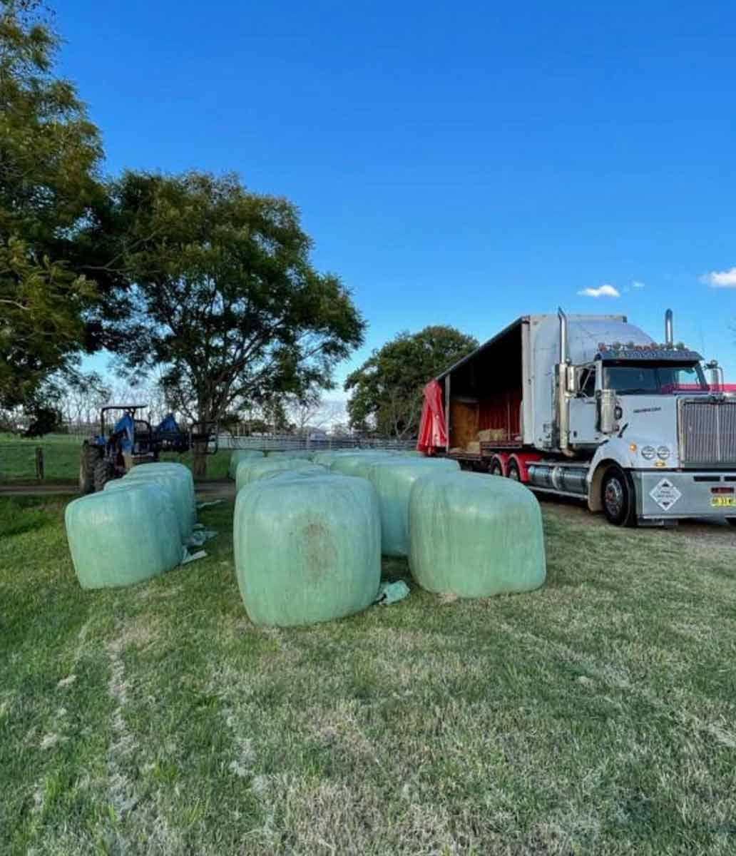 A Truck Is Carrying Bales Of Hay In A Field — Dillon Rural In Nabiac, NSW