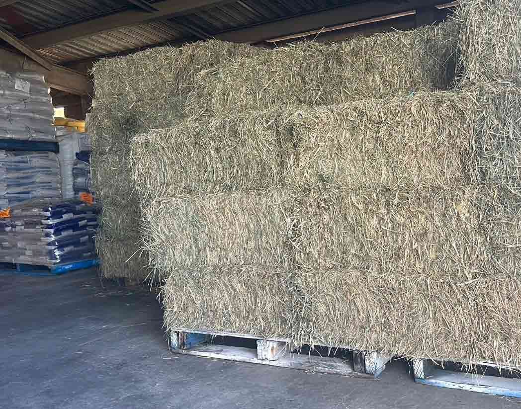 A Stack Of Hay Bales Sitting On Top Of Wooden Pallets In A Warehouse — Dillon Rural In Cundletown, NSW
