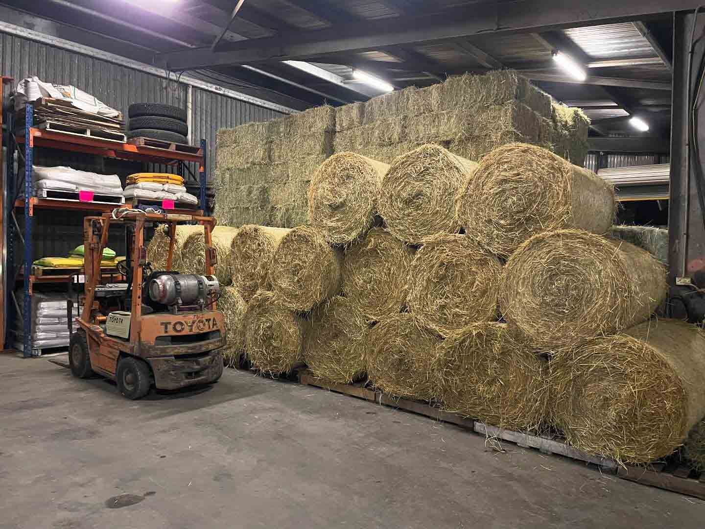 A Forklift Is Driving Through A Warehouse Filled With Bales Of Hay — Dillon Rural In Cundletown, NSW