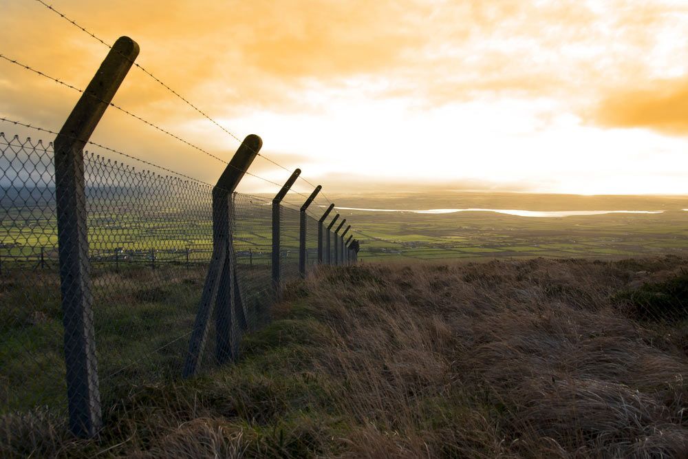 A Barbed Wire Fence Surrounds A Field At Sunset — Dillon Rural In Cundletown, NSW