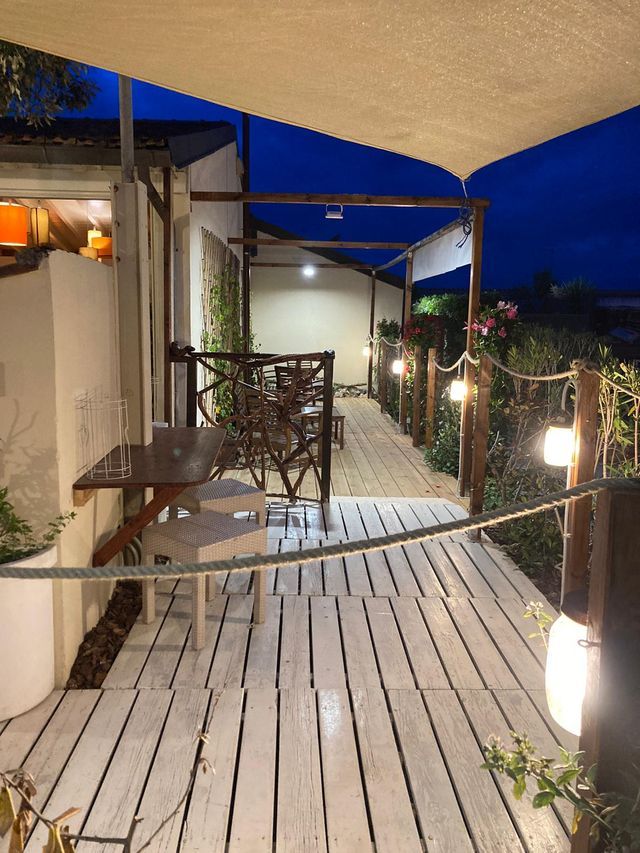 Una terrazza in legno con tavolo e sedie è illuminata di notte.