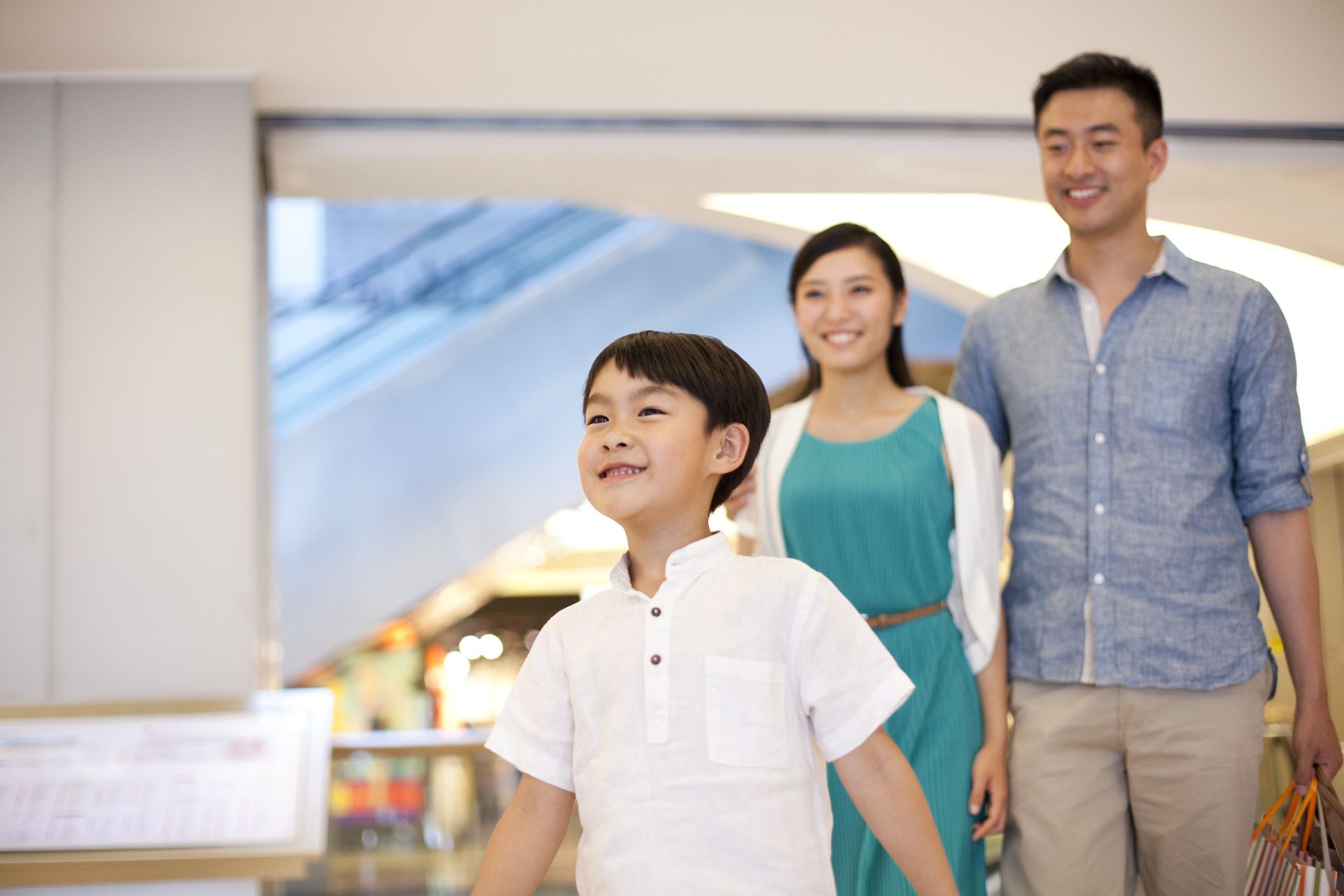 A family is walking through a shopping mall holding hands.