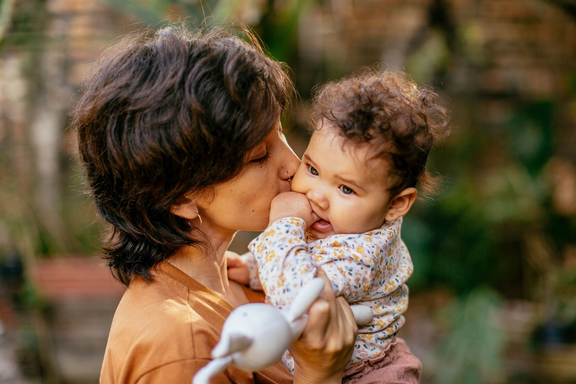 A woman is kissing a baby on the cheek.