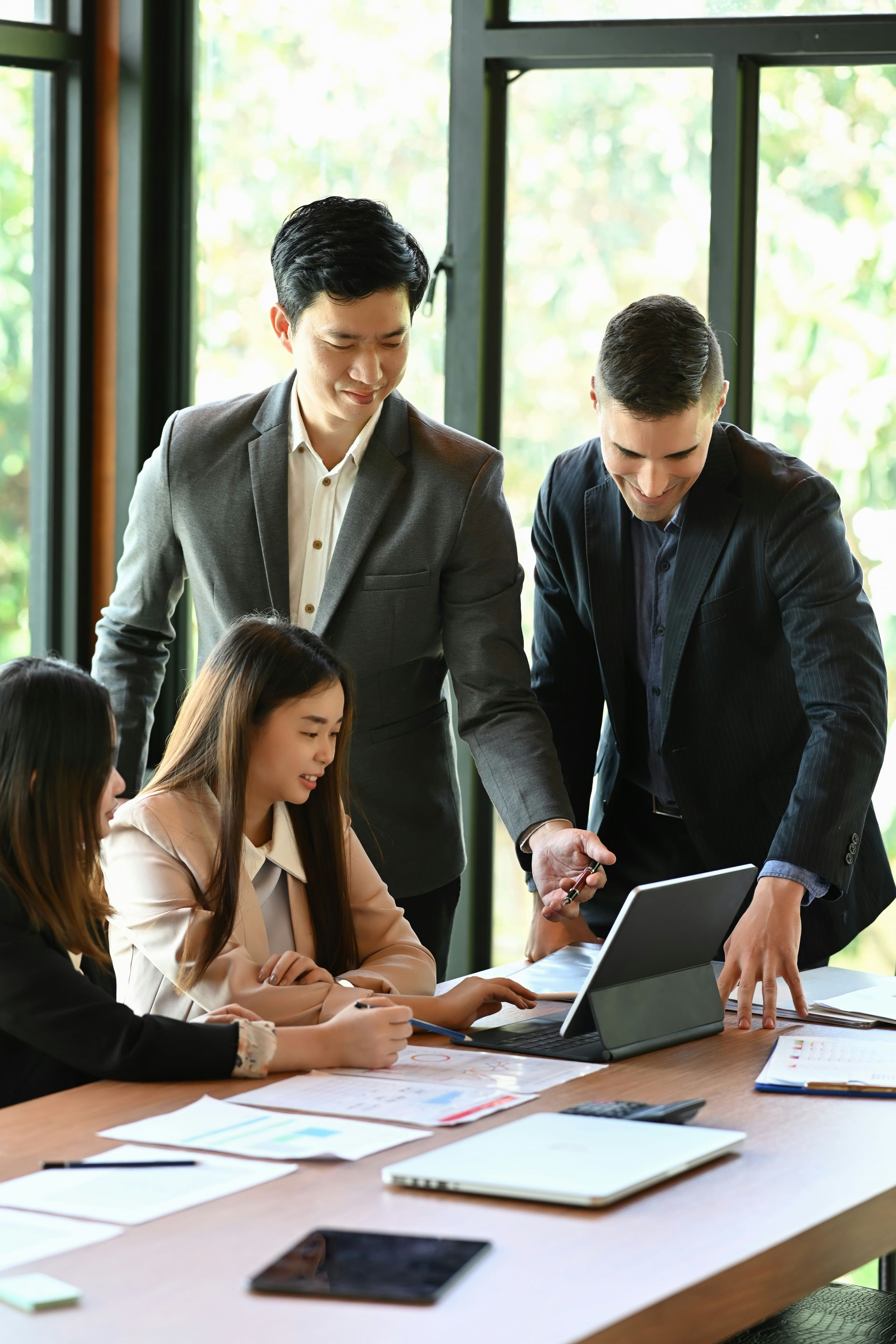 A group of business people are sitting around a table looking at a laptop.