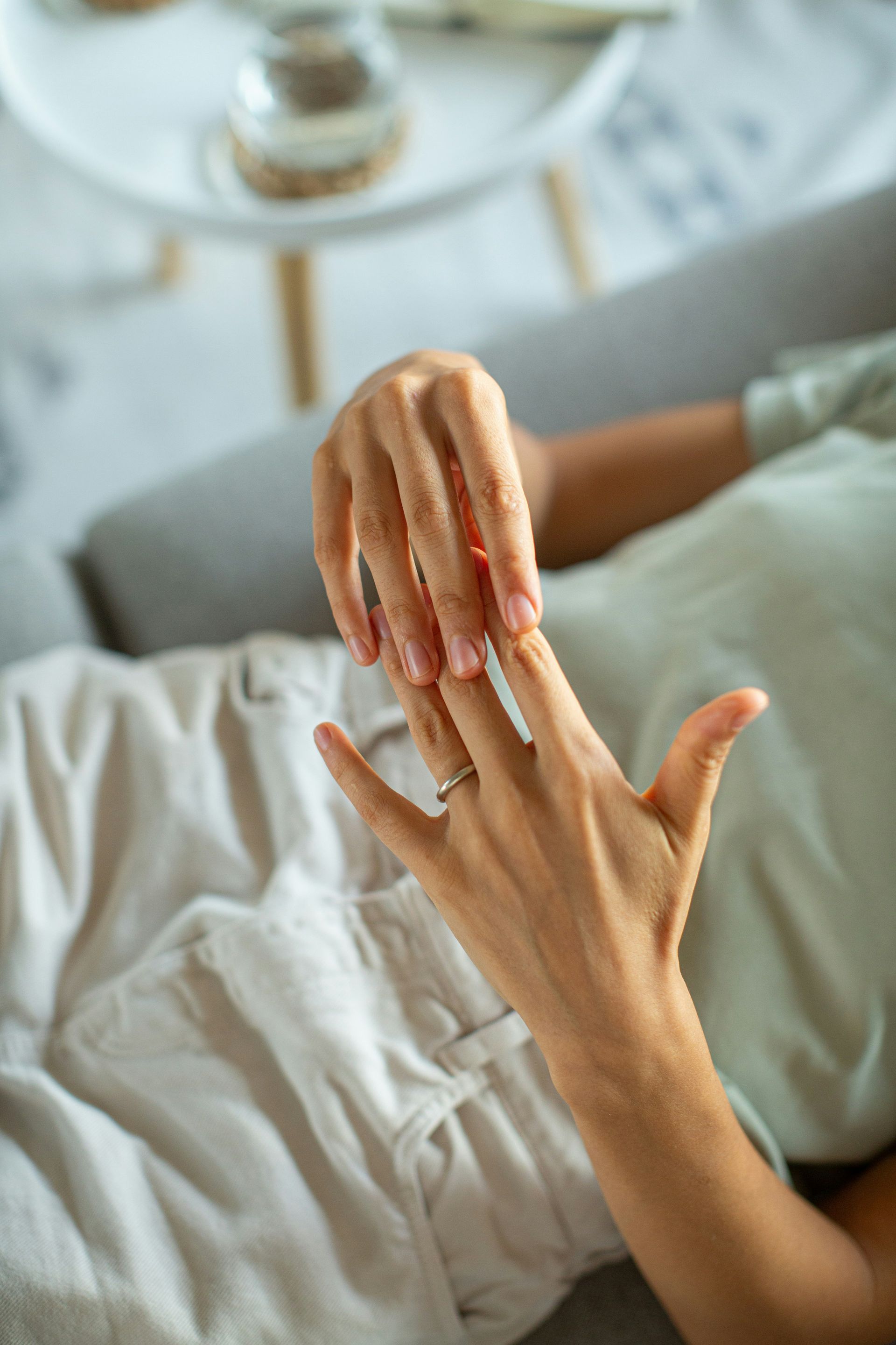 A woman is laying on a couch and touching her nails.