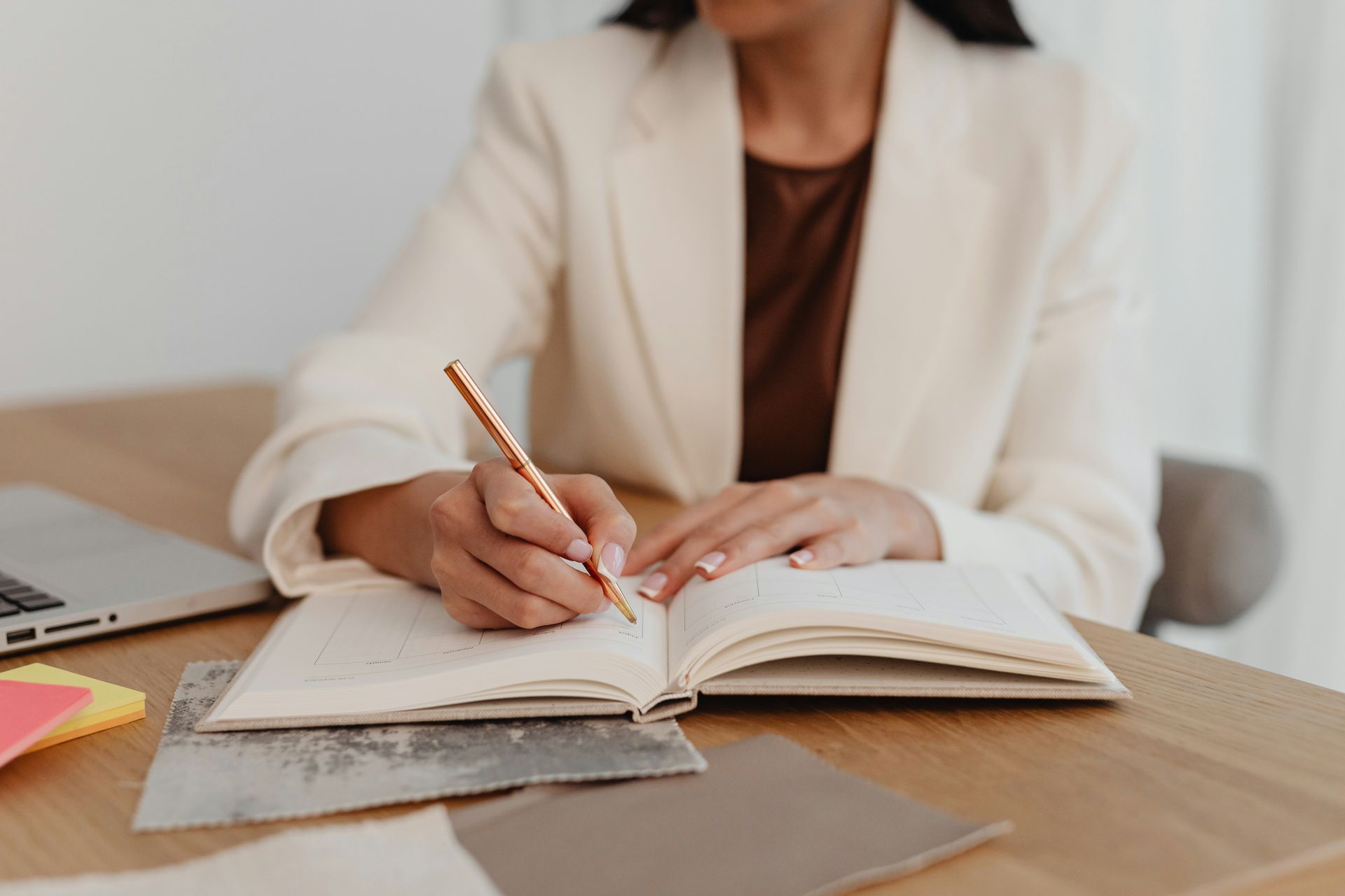A woman is sitting at a table writing in a notebook.