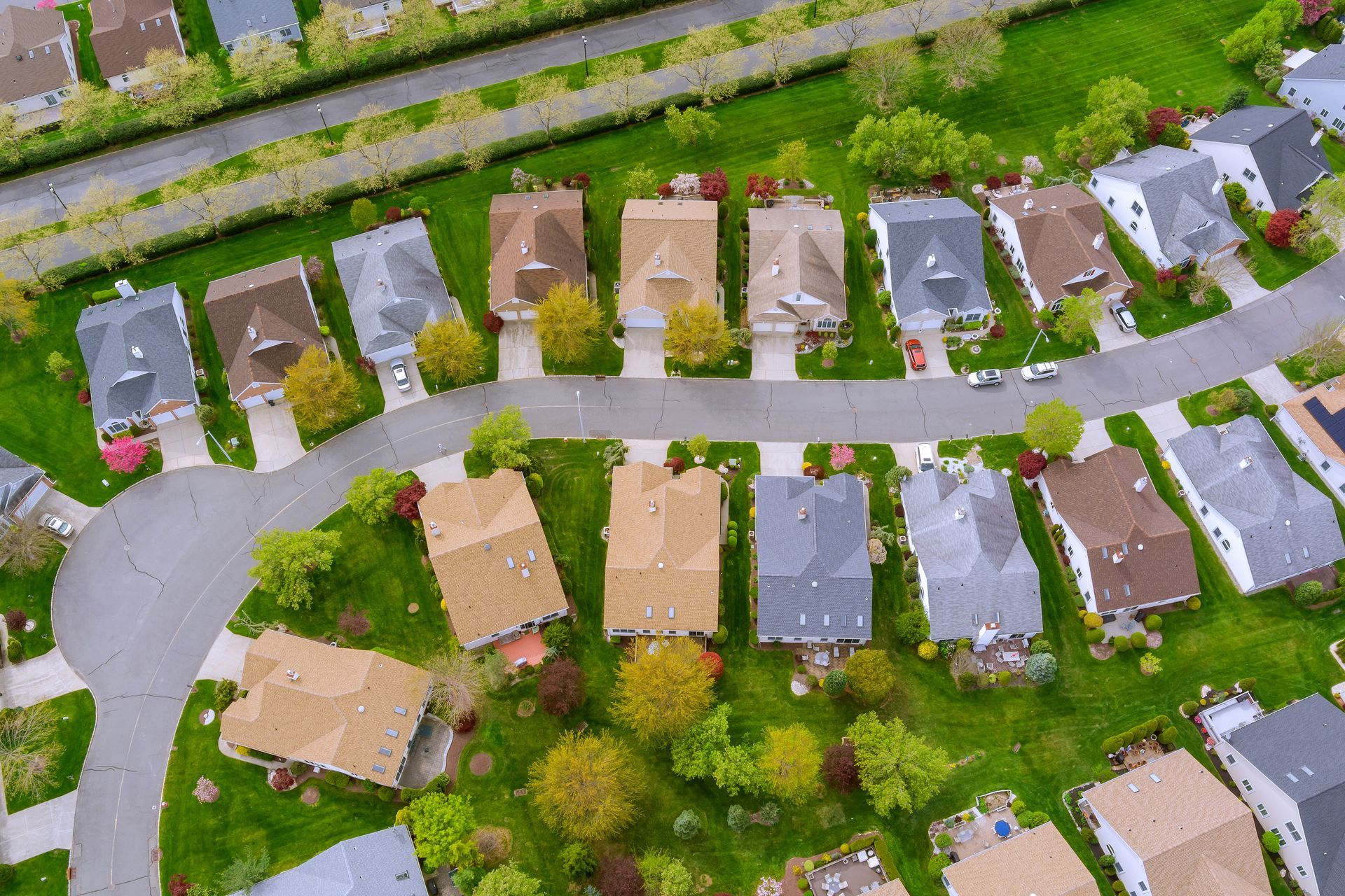 Aerial view of a suburban neighborhood with rows of houses, trees, and winding streets