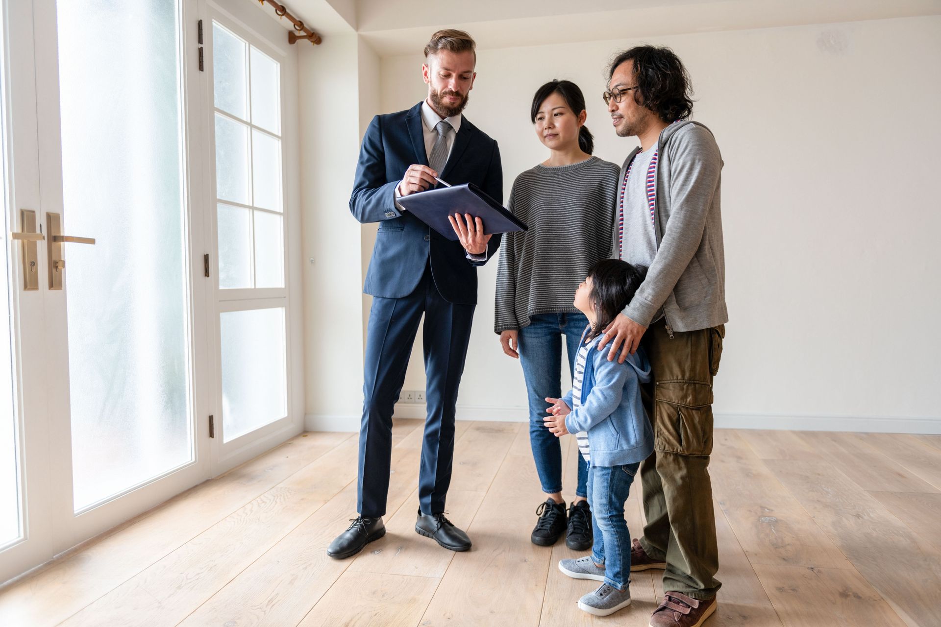 Real estate agent showing a house to a couple and child in an empty room