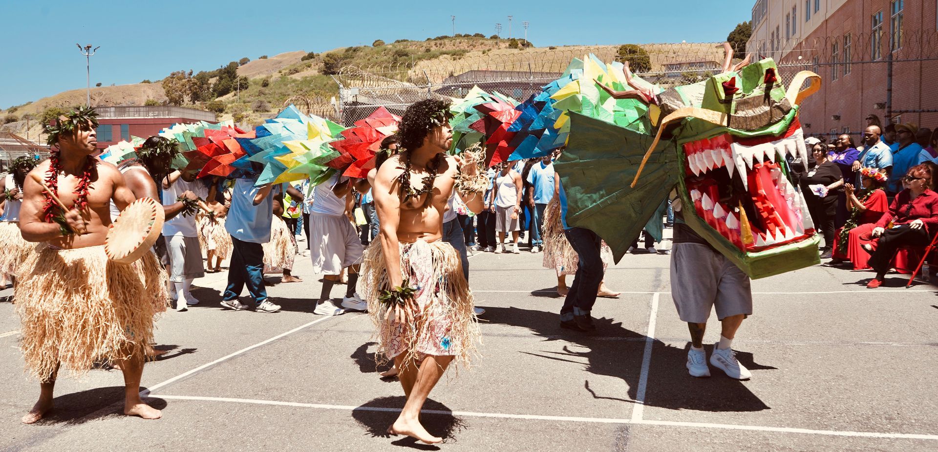 Dancers in colorful costumes perform a street parade with a dragon float in the background.