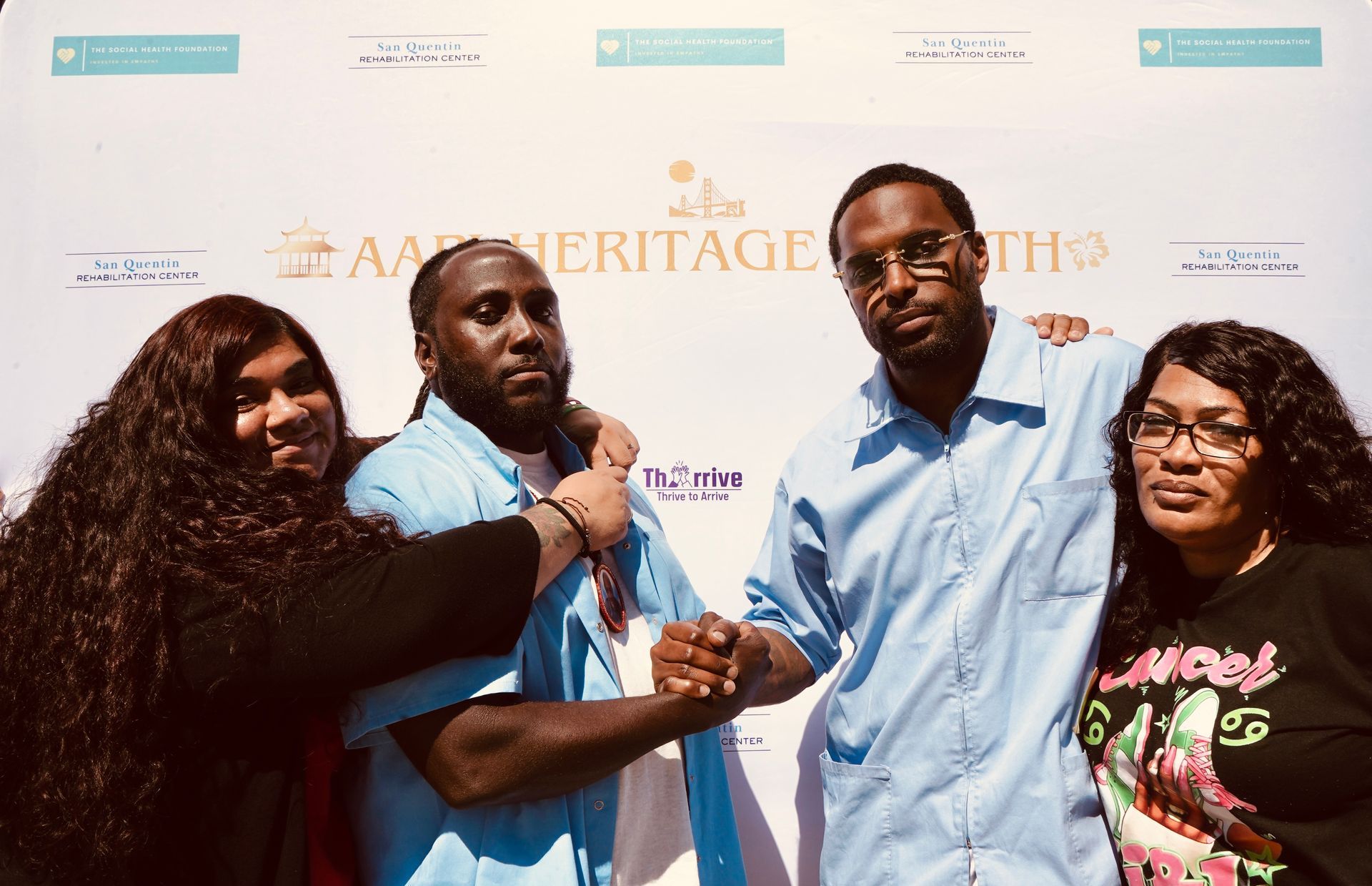 Four people standing and smiling at a step-and-repeat event backdrop