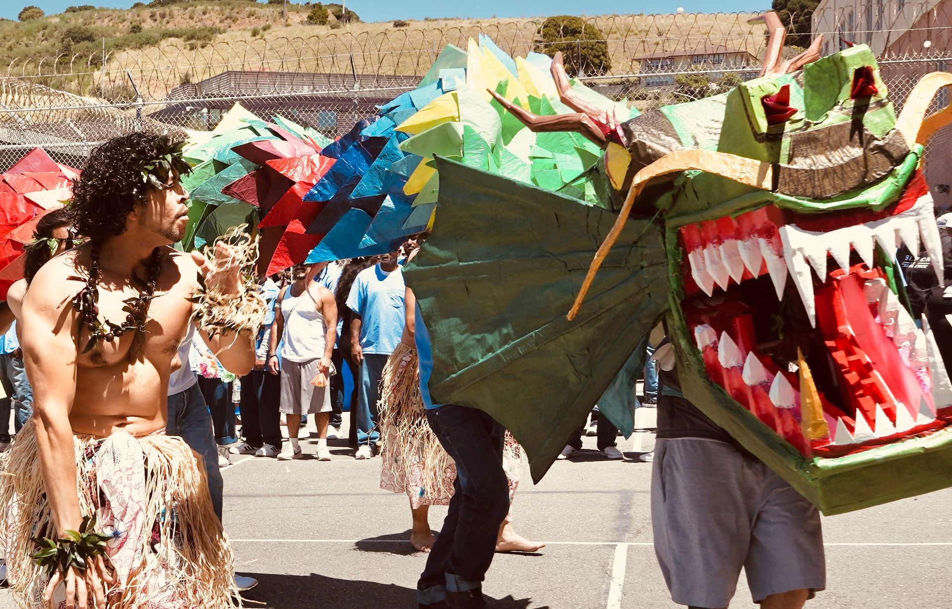 People in colorful dragon costumes performing at an outdoor festival, with crowds watching nearby.