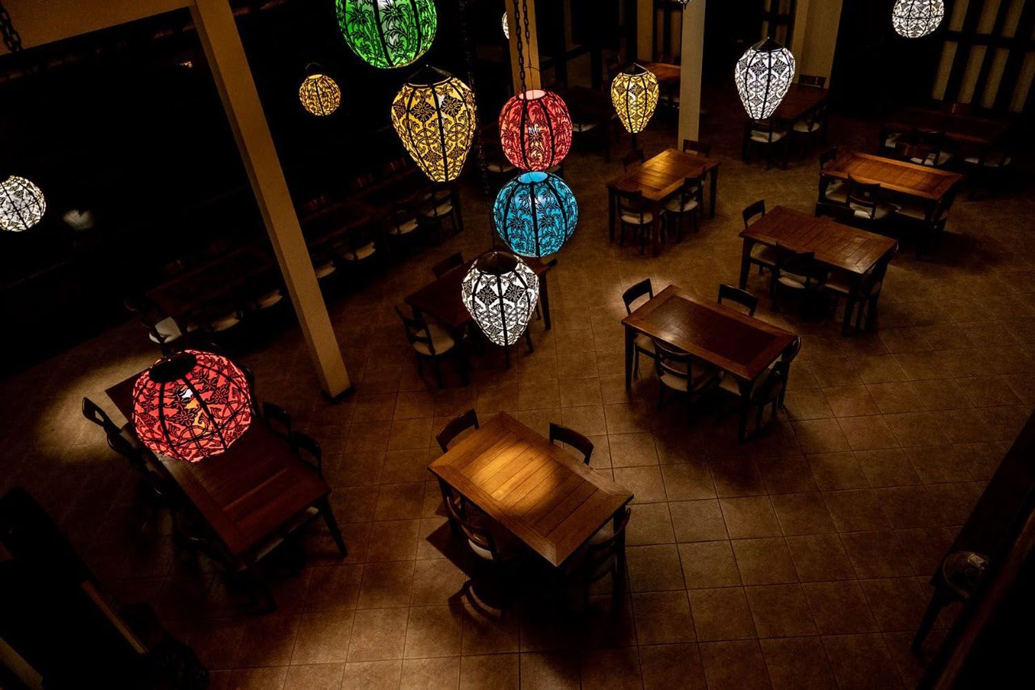Um restaurante com mesas e cadeiras e lanternas penduradas no teto