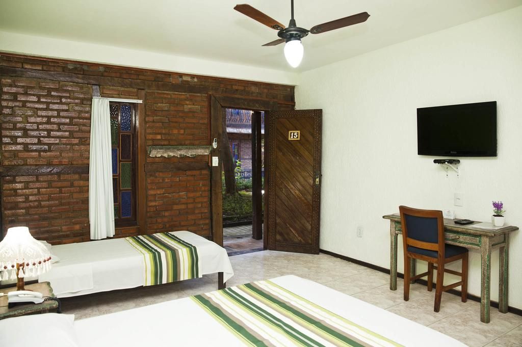 Um quarto com duas camas, uma escrivaninha e uma TV de tela plana
