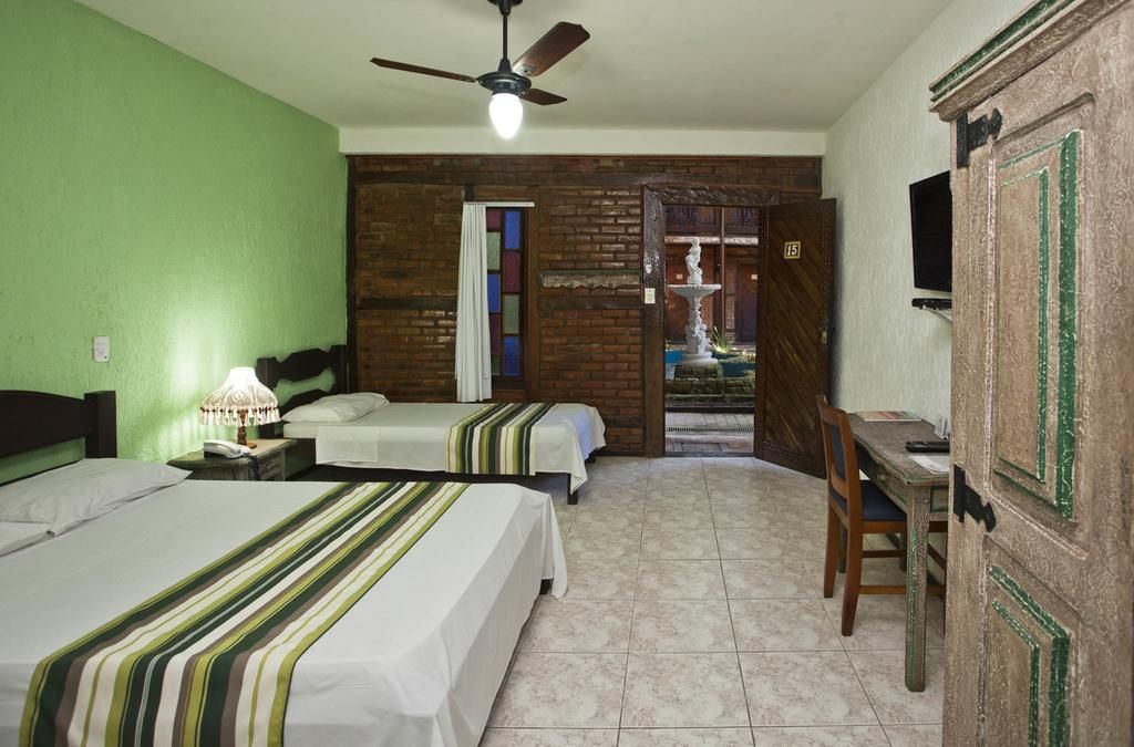 Um quarto de hotel com três camas e um ventilador de teto
