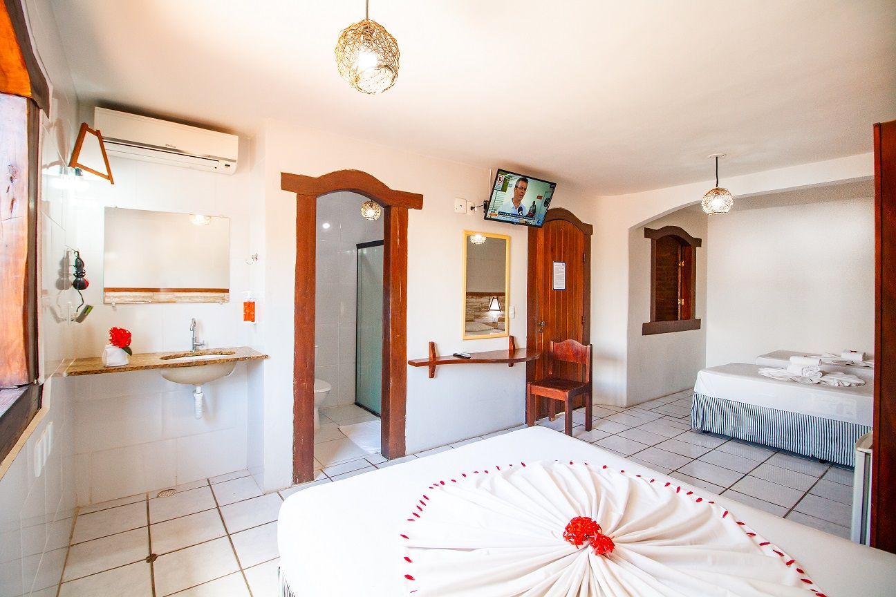 Um quarto de hotel com duas camas, uma pia e uma televisão.