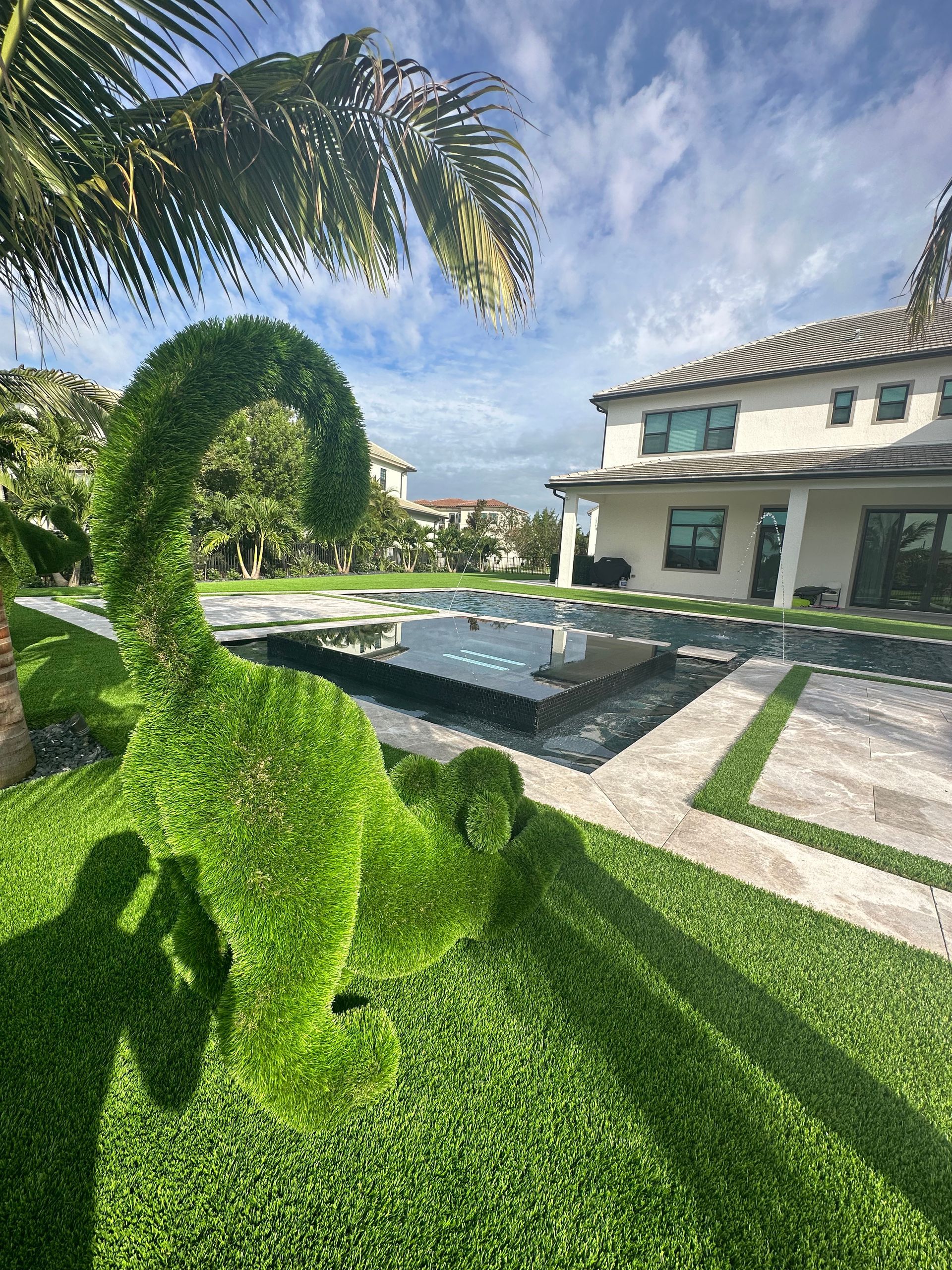 Artificial turf surrounding pool in South Florida with an artificial grass animal in 3D.