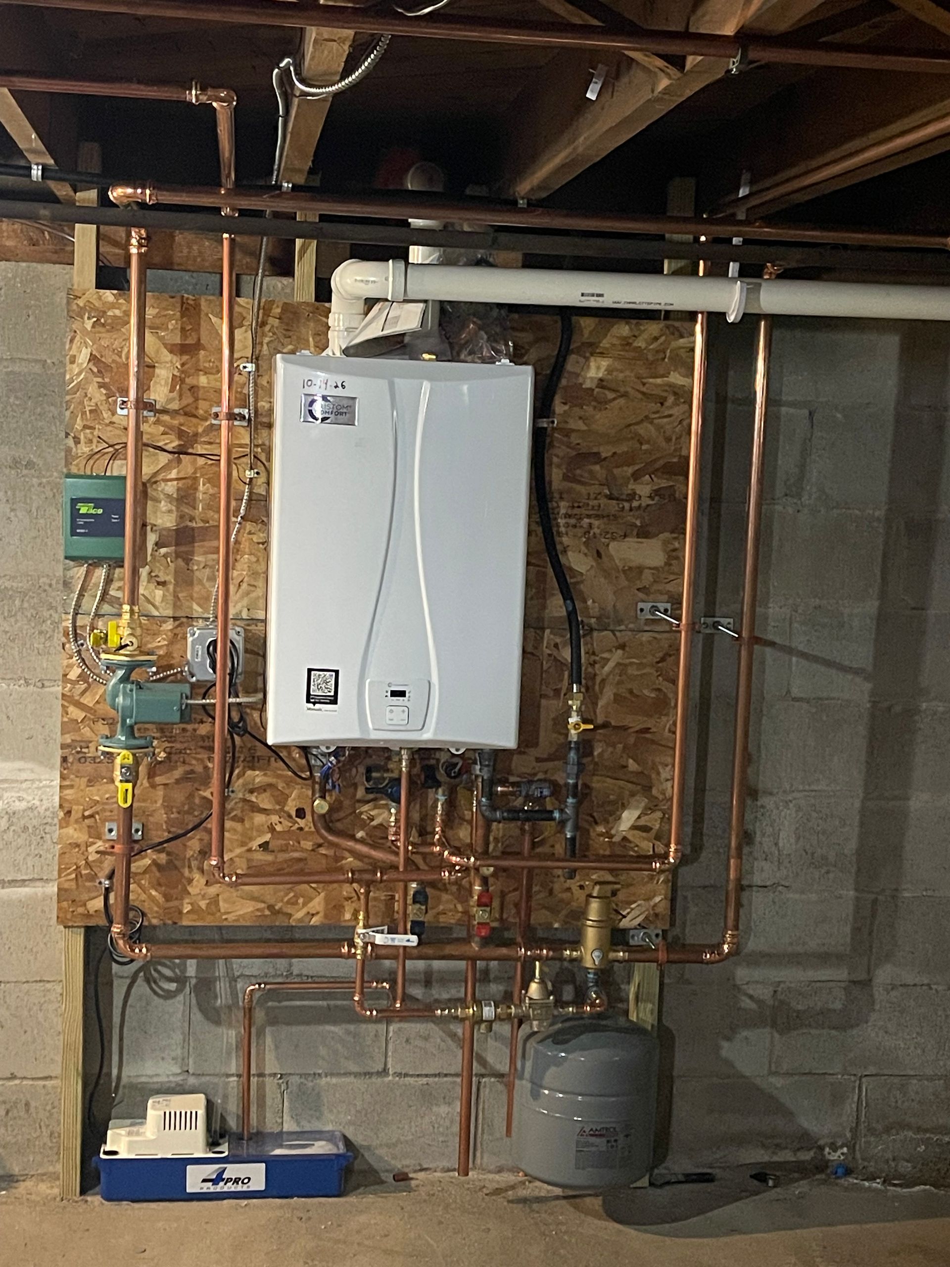 Basement utility wall with water heater, exposed pipes, and a furnace on concrete floor
