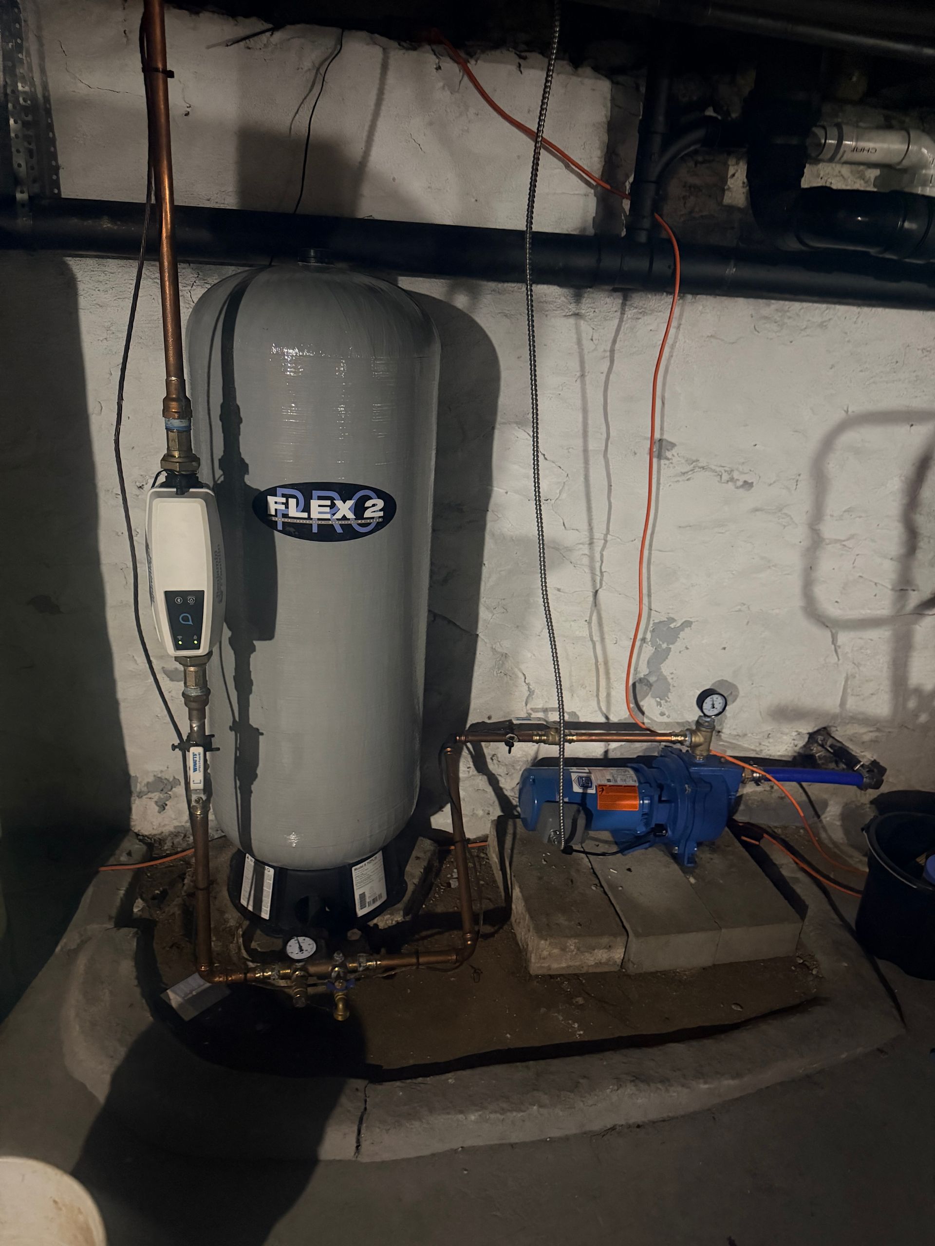 Basement utility room with a water heater, blue pump, pipes, and exposed wiring against a concrete wall