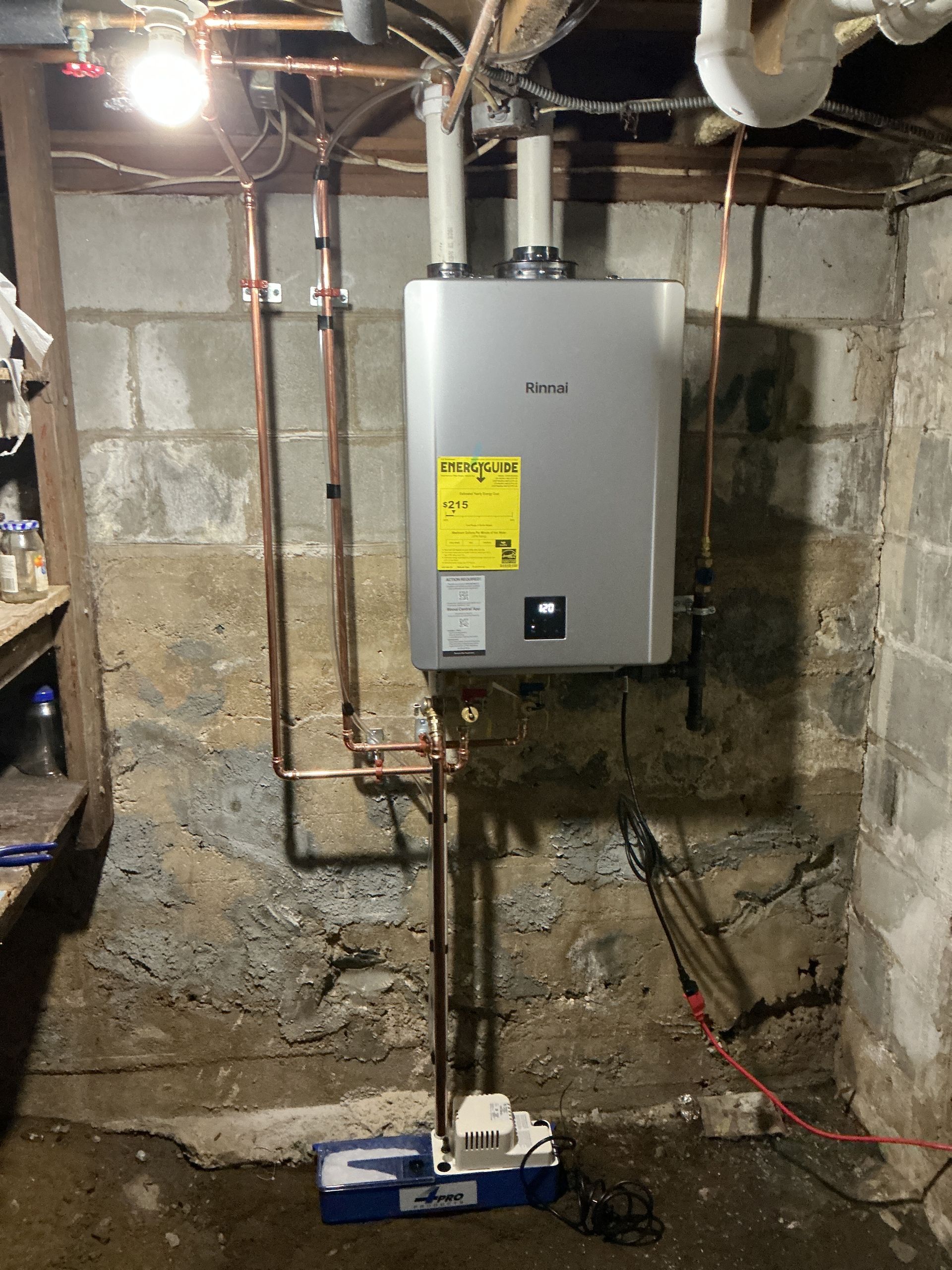 Basement utility area with a wall-mounted water heater, exposed pipes, and concrete block walls.