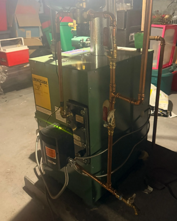 Green industrial machine with copper pipes in a workshop or factory setting