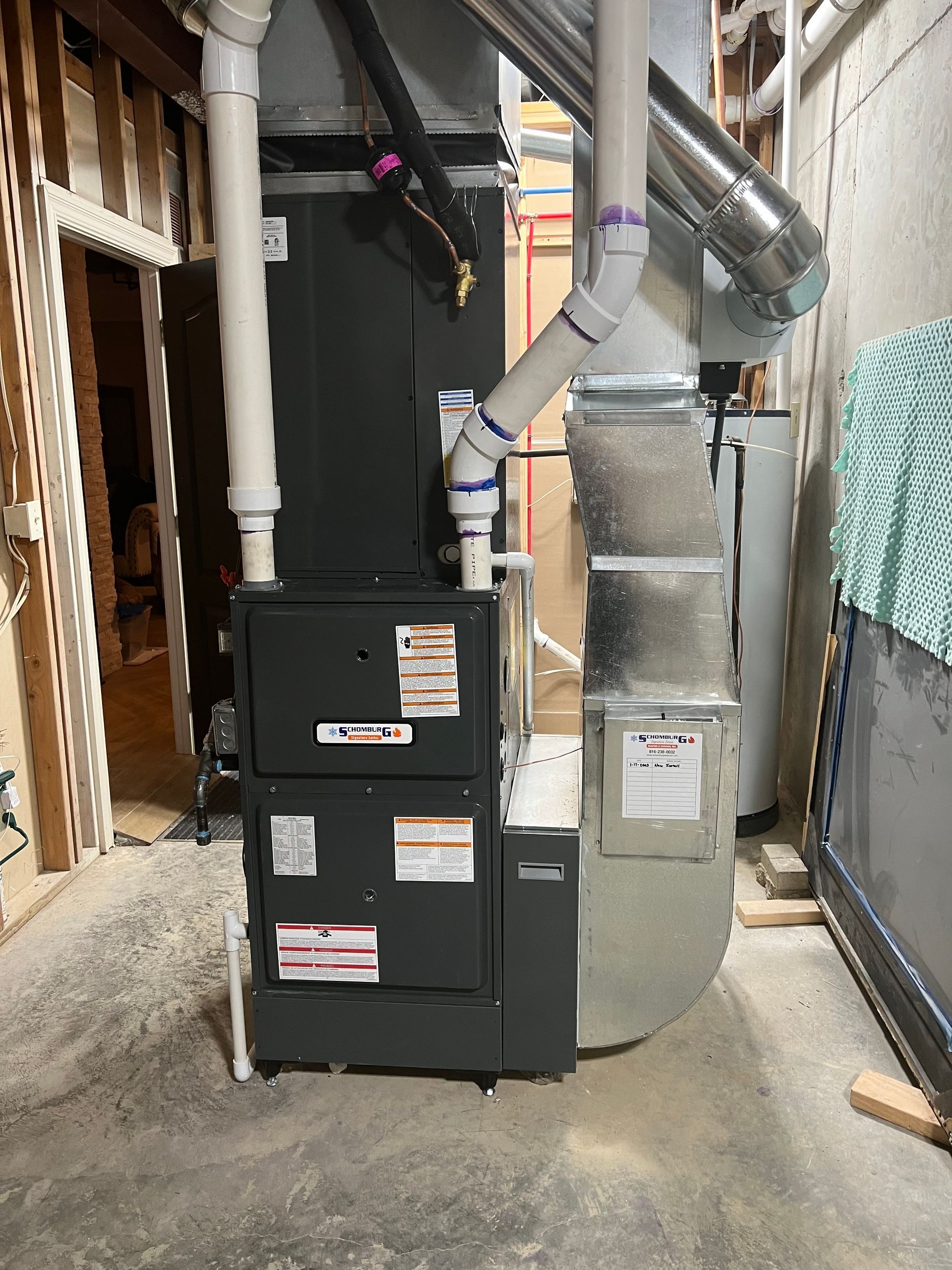 Furnace unit with white PVC pipes and silver ductwork in a basement setting.