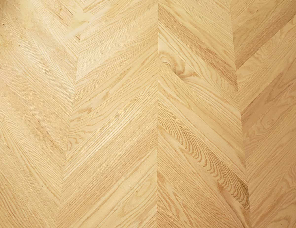 Parquet en bois clair à motif chevrons.