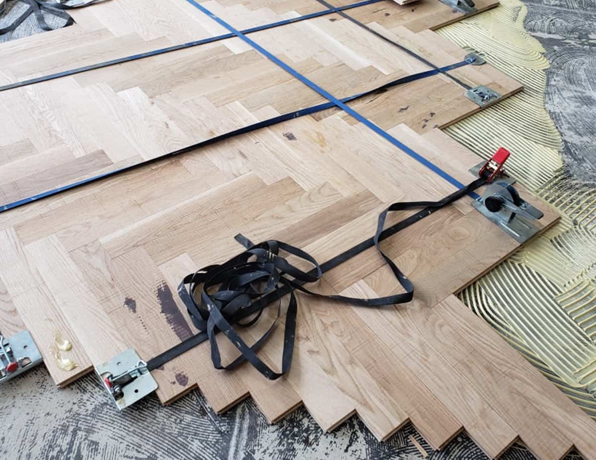 Installation de plancher de bois franc à chevrons avec sangles et pinces.