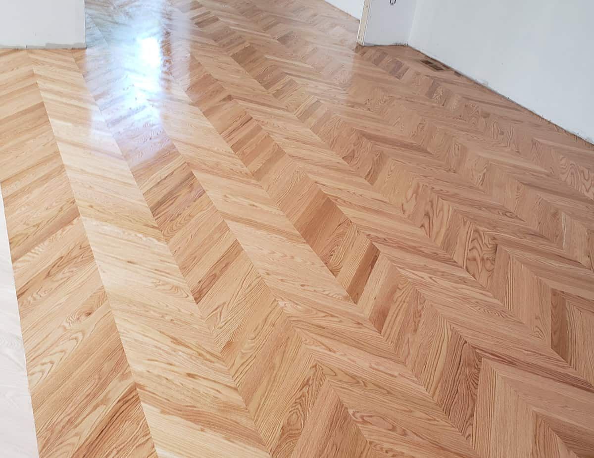 Parquet en bois à chevrons, marron clair avec une finition brillante.