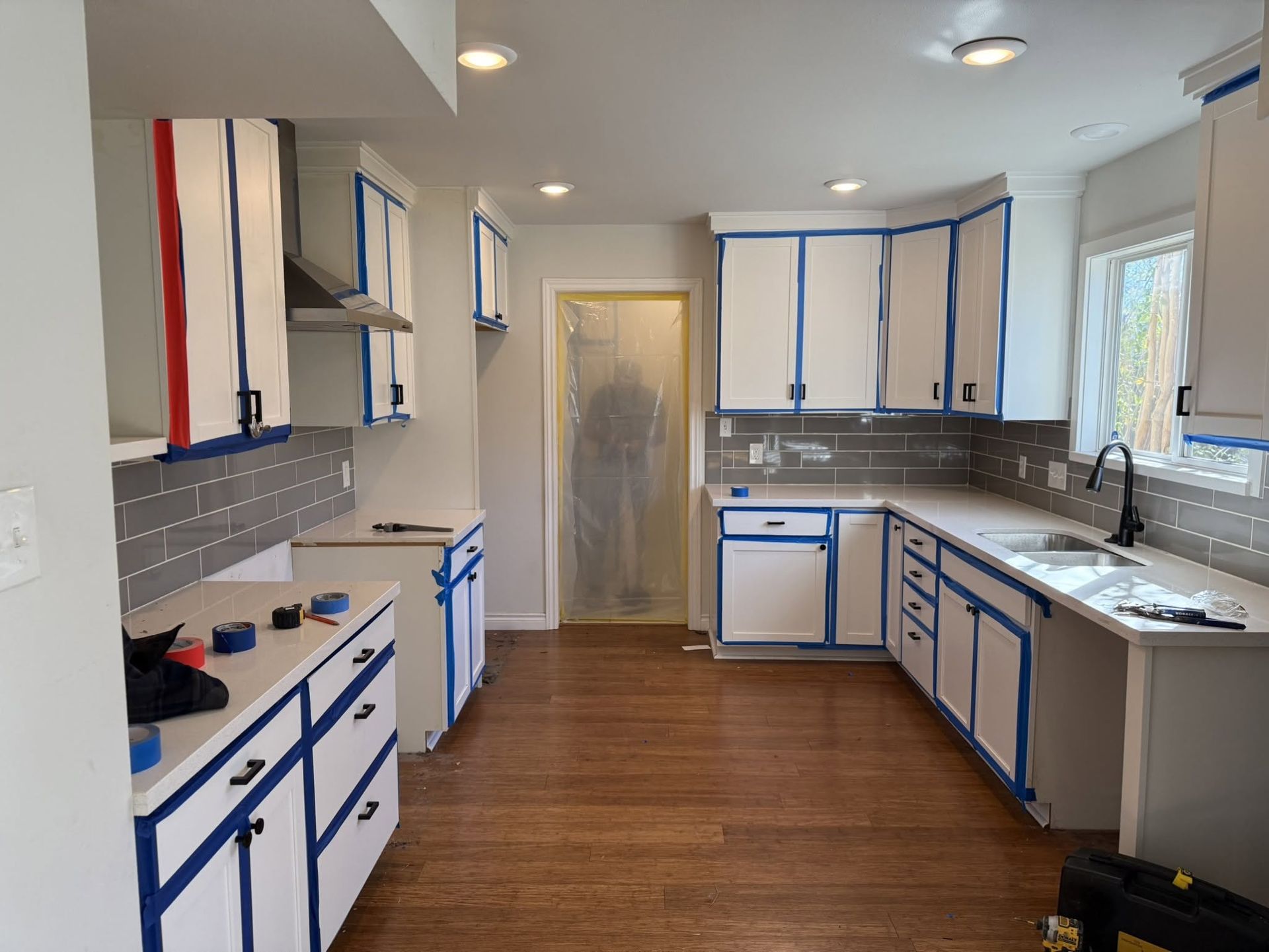 Bright kitchen with white cabinets, blue trim, stainless appliances, and wood floors.