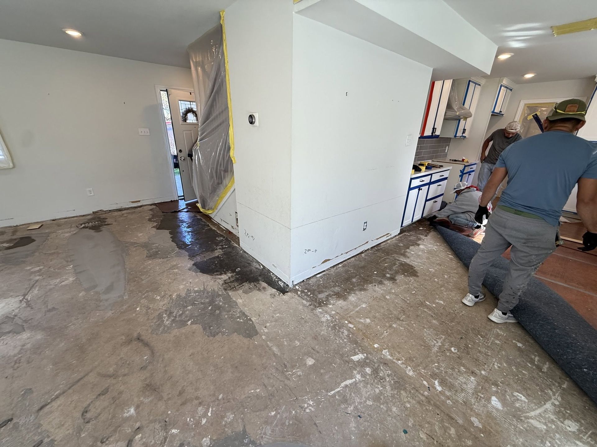 Damaged interior hallway with water damage, debris, and a worker inspecting the floor
