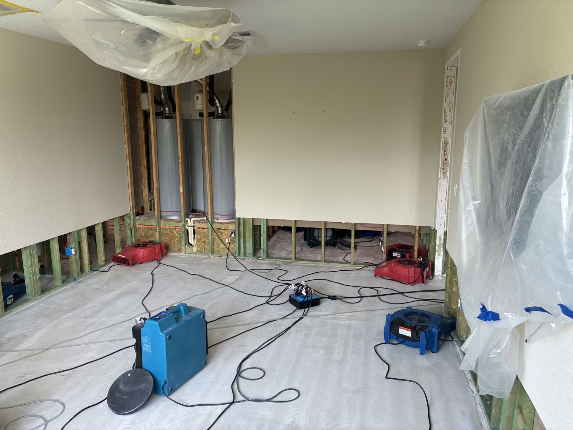 Renovation room with plastic-covered floor, exposed wall studs, tools, and construction materials
