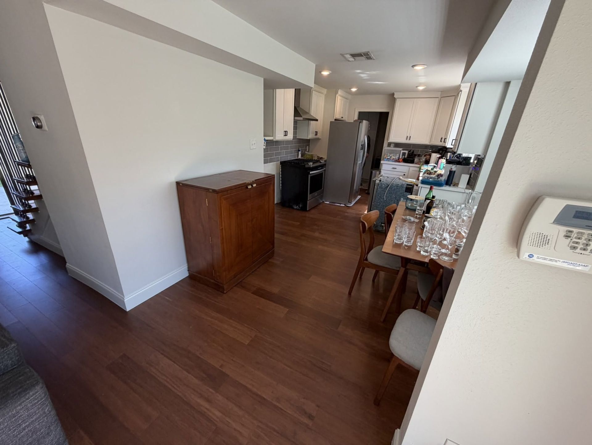 Open kitchen and dining area with wood floors, dark cabinets, and a small table near the right wall.
