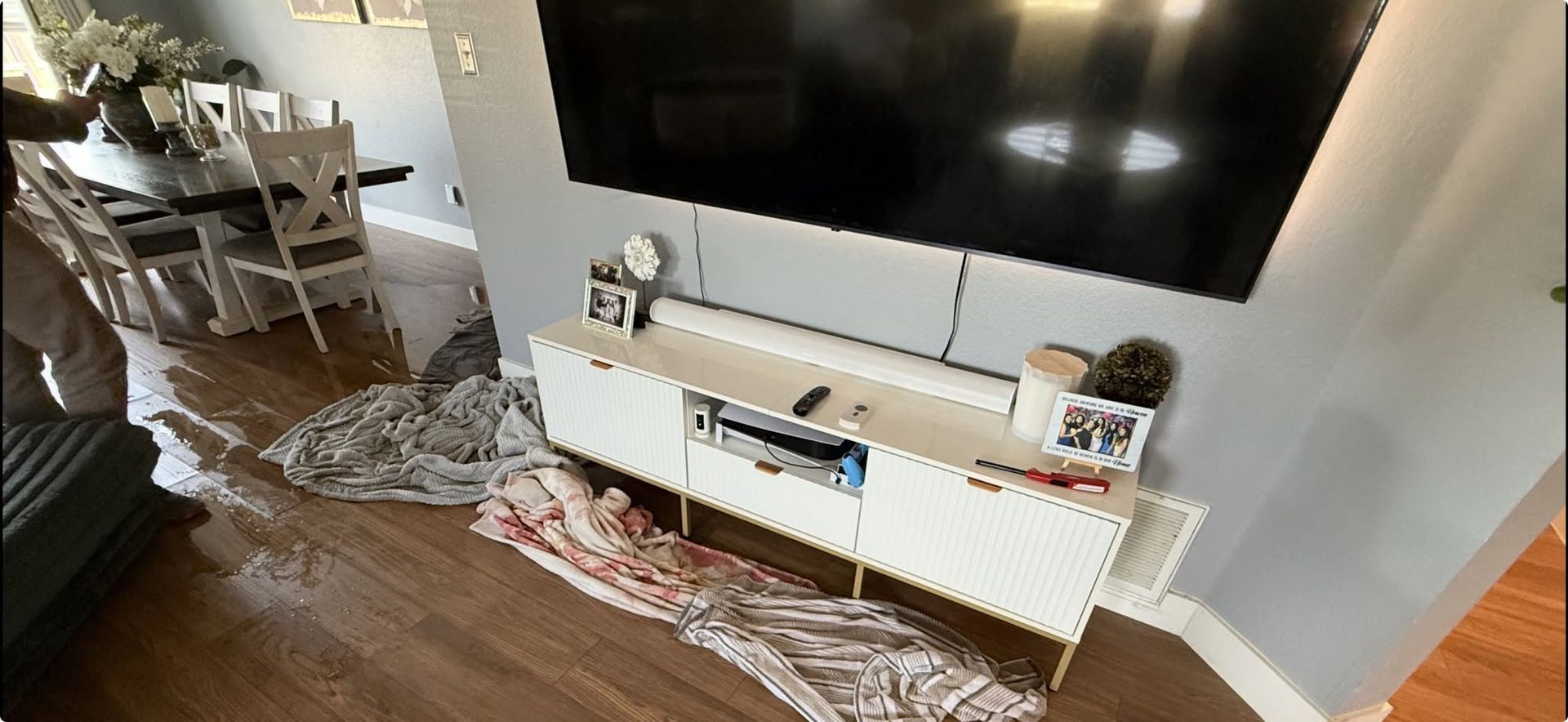 Living room with TV, white console, rug, and dining table in the background