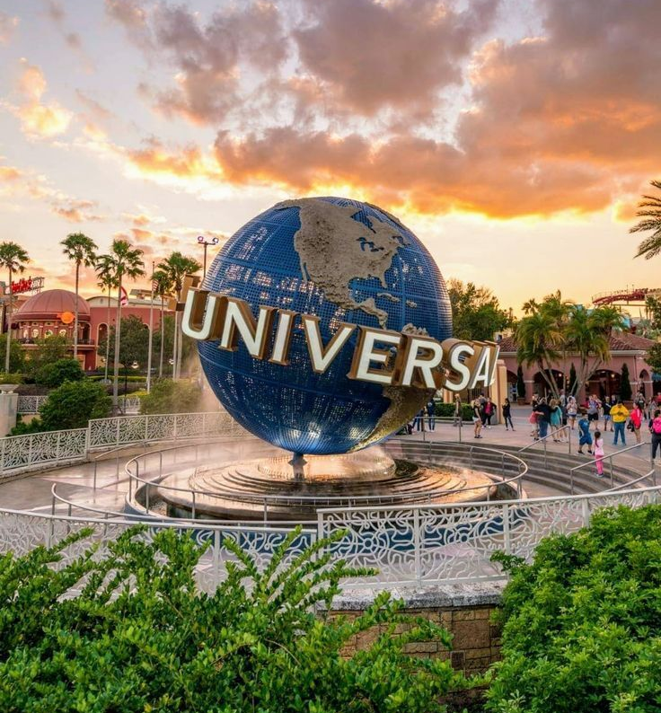 Universal globe fountain at sunset with visitors in the theme park plaza