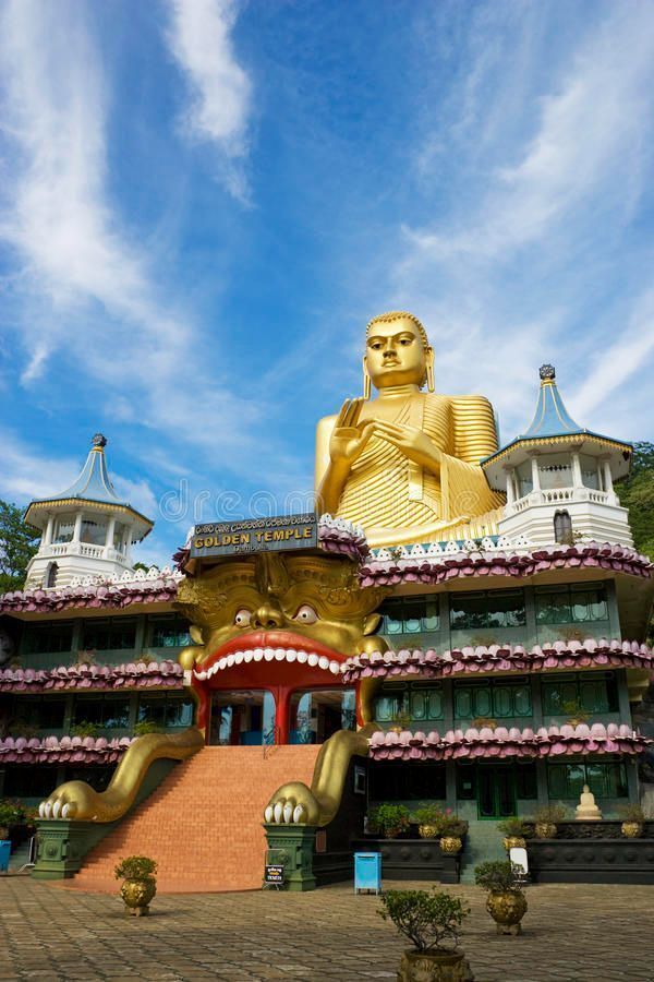 Golden Buddha statue atop a colorful temple against a blue sky