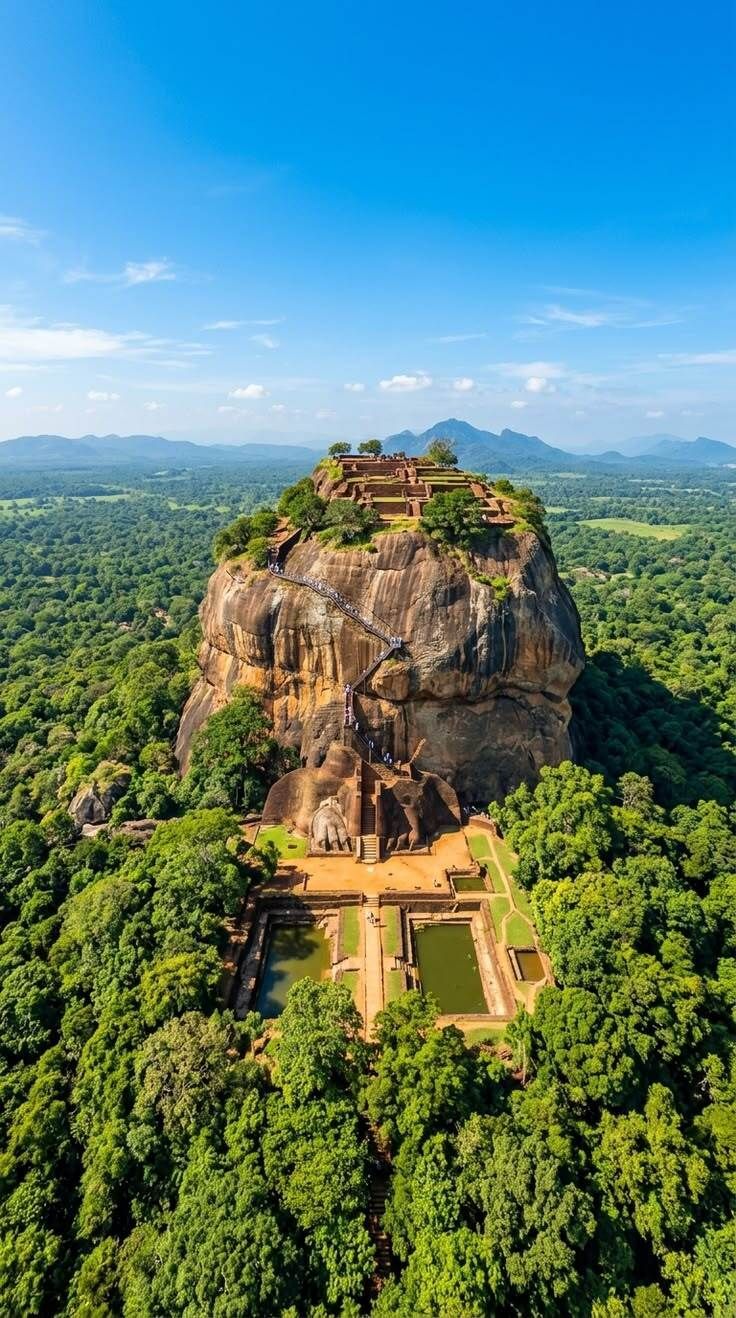 Ancient temple atop a towering rocky hill, surrounded by dense green forest under a blue sky.