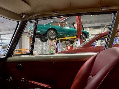 Green car on lift in garage, viewed from another car. Green car on lift in garage, viewed from another car.