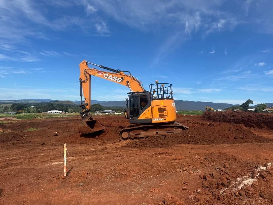 A Yellow Truck Is Spraying Water on A Dirt Road — Watto's Earthmoving & Machinery Hire in Atherton, QLD