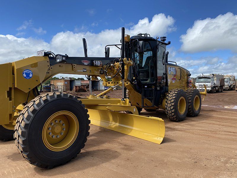 A Yellow Tractor Is Parked in A Dirt Lot — Watto's Earthmoving & Machinery Hire in Atherton, QLD