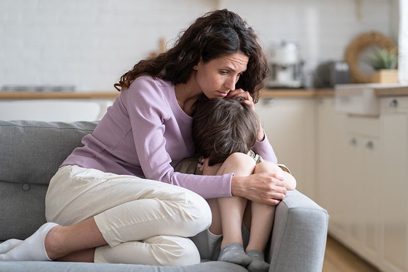 a woman sitting on a couch hugging a child
